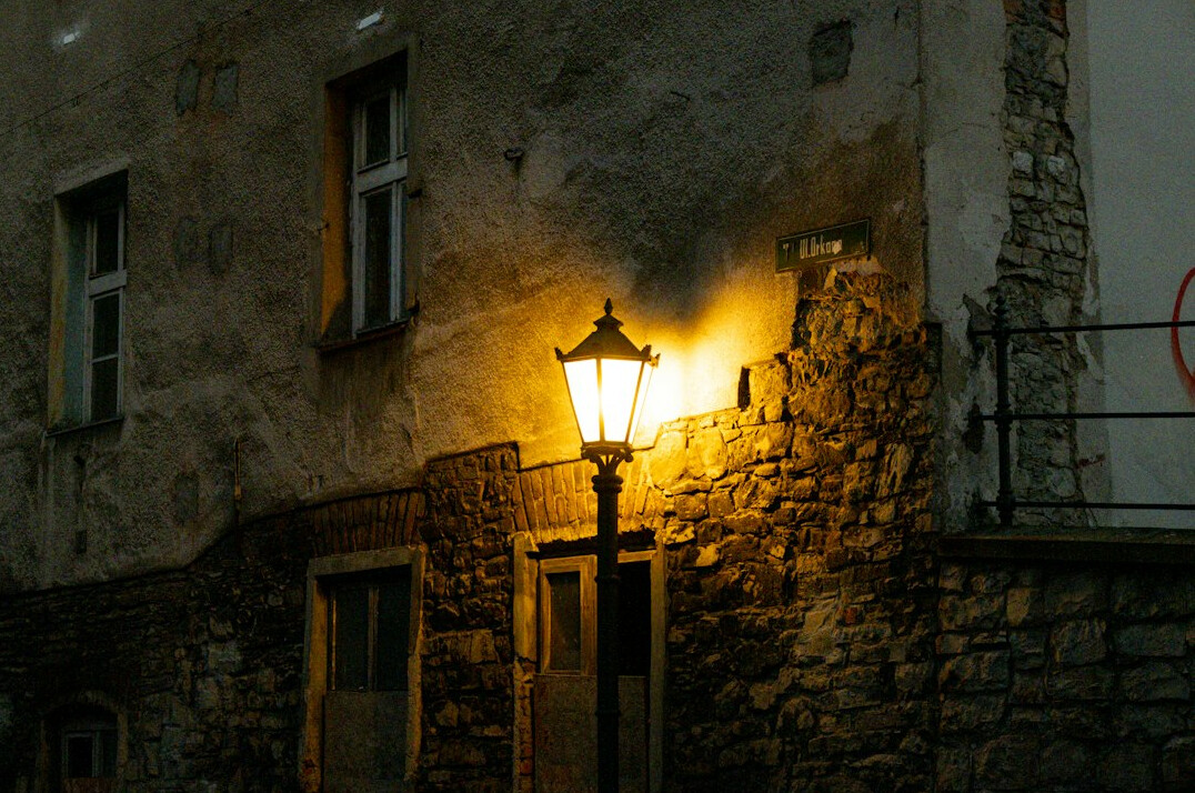 Foggy old European street at night lit by a lamp