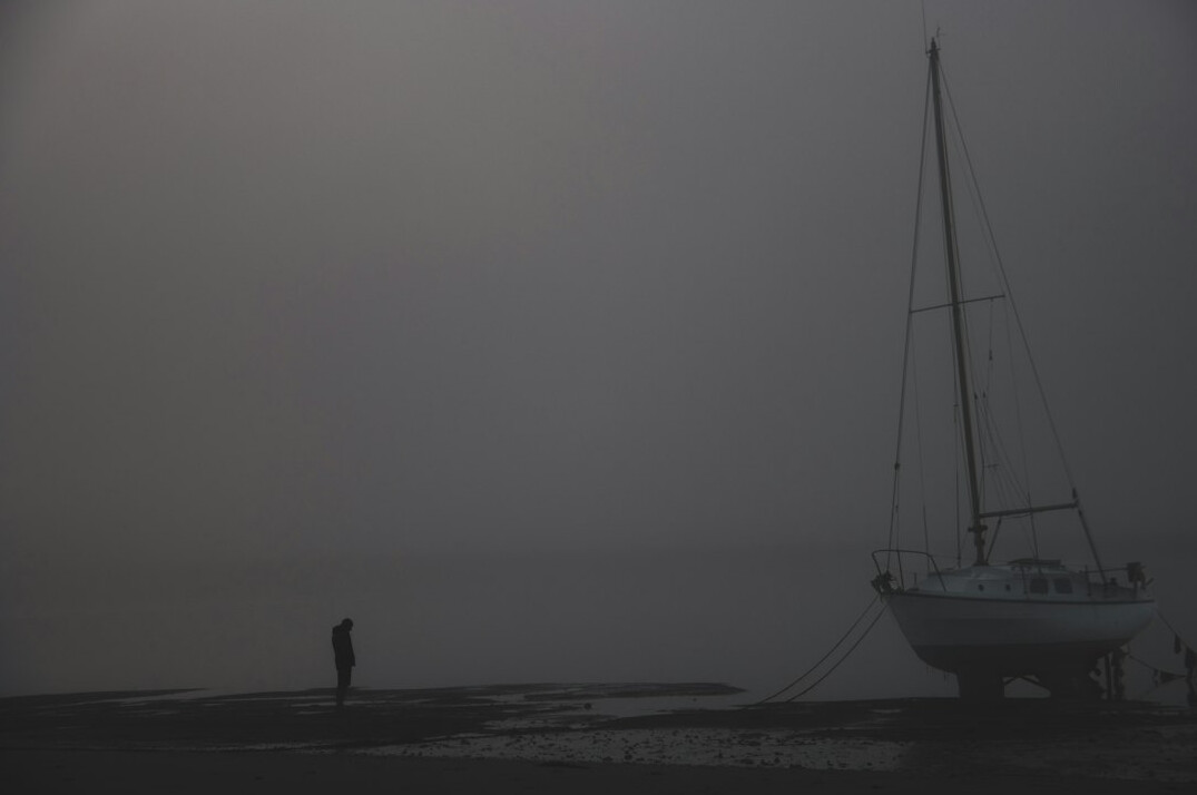 Foggy harbor at dusk with the silhouette of a lone figure